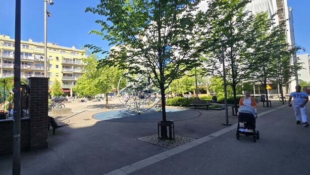 Um parque público com parque infantil, bancos e uma trilha para pedestres.