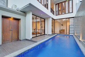 Une maison moderne dotée d’une piscine, de grandes fenêtres et d’un balcon.