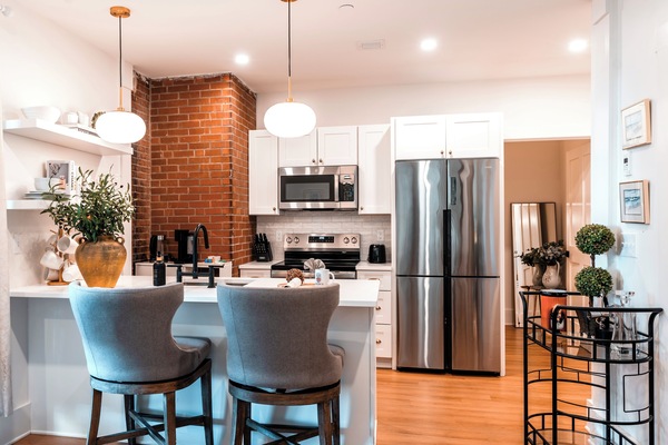 Stylish kitchen with brick accent, modern appliances, and a cozy breakfast bar.