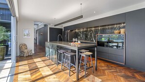 Une cuisine moderne dotée d’un plan de travail en marbre, de tabourets de bar et d’un réfrigérateur encastré.