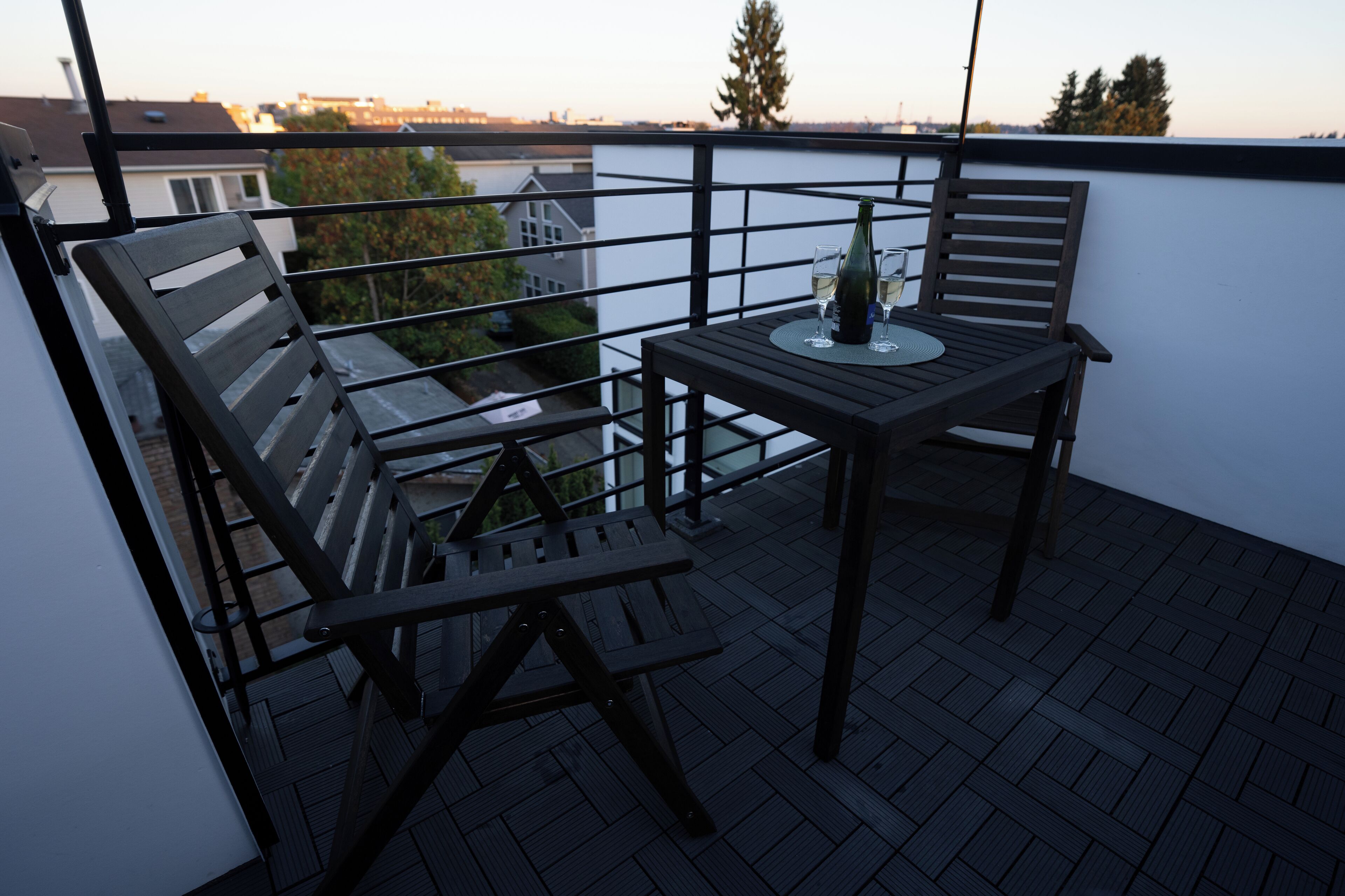 En balkon med et bord og to stole, en flaske og to glas.