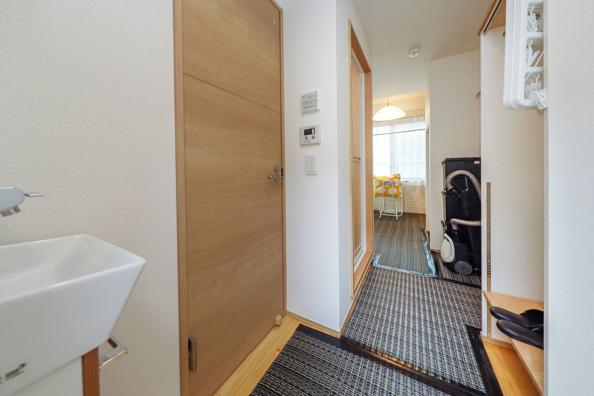 A hotel bathroom with a wooden door, a white sink, and a shower area with a towel rack.
