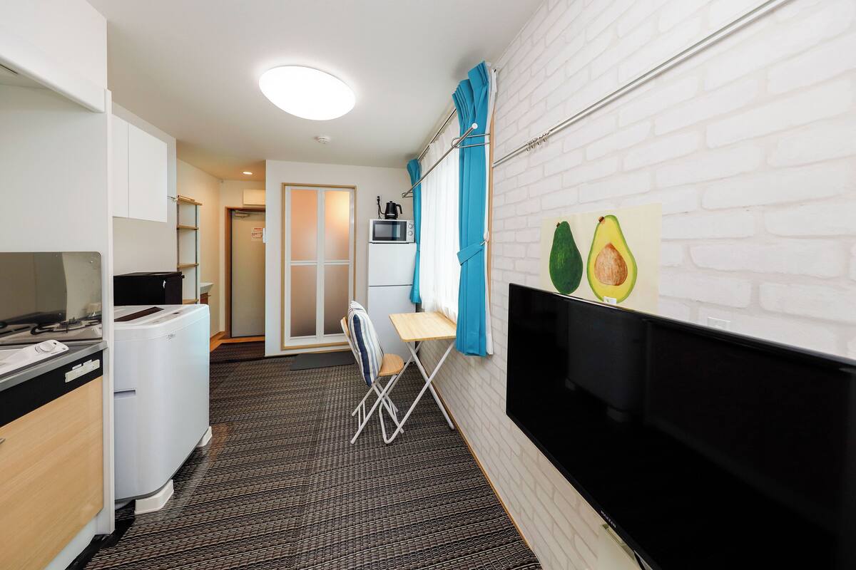 A compact kitchenette with a microwave, a small table, and a chair.