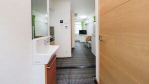 A narrow hallway with a white sink, a mirror, and a wooden door. - Zenith Shinjuku Hinoki Building A (Tokyo)