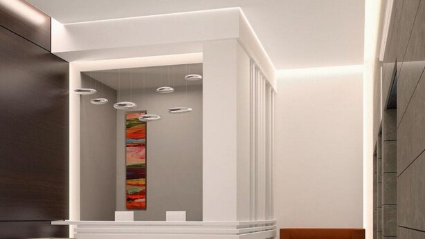 A modern interior with a white reception desk, a colorful abstract painting, and recessed lighting. - Staybridge Suites DOHA LUSAIL by IHG (Lusail)