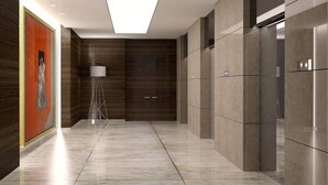A modern hallway with a floor-to-ceiling mirror, a standing lamp, and a door with a glass panel. - Staybridge Suites DOHA LUSAIL by IHG (Lusail)
