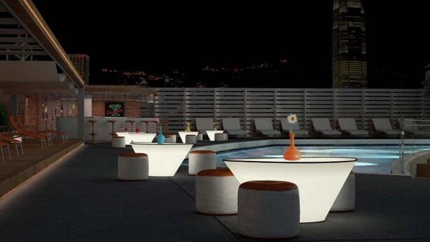 Een dakterras met loungezitting, een zwembad en uitzicht op de stadshemel bij nacht.