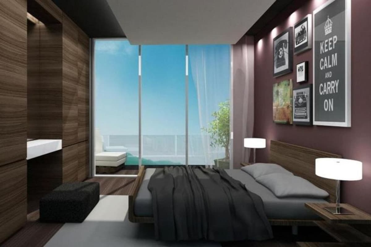 A modern bedroom with a large bed, bedside tables, a nightstand, a window with a view, and a wall with framed pictures.