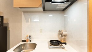 A modern kitchen with a stainless steel sink, a built-in stove, and wooden cabinets. - b&Namba3 (Osaka)