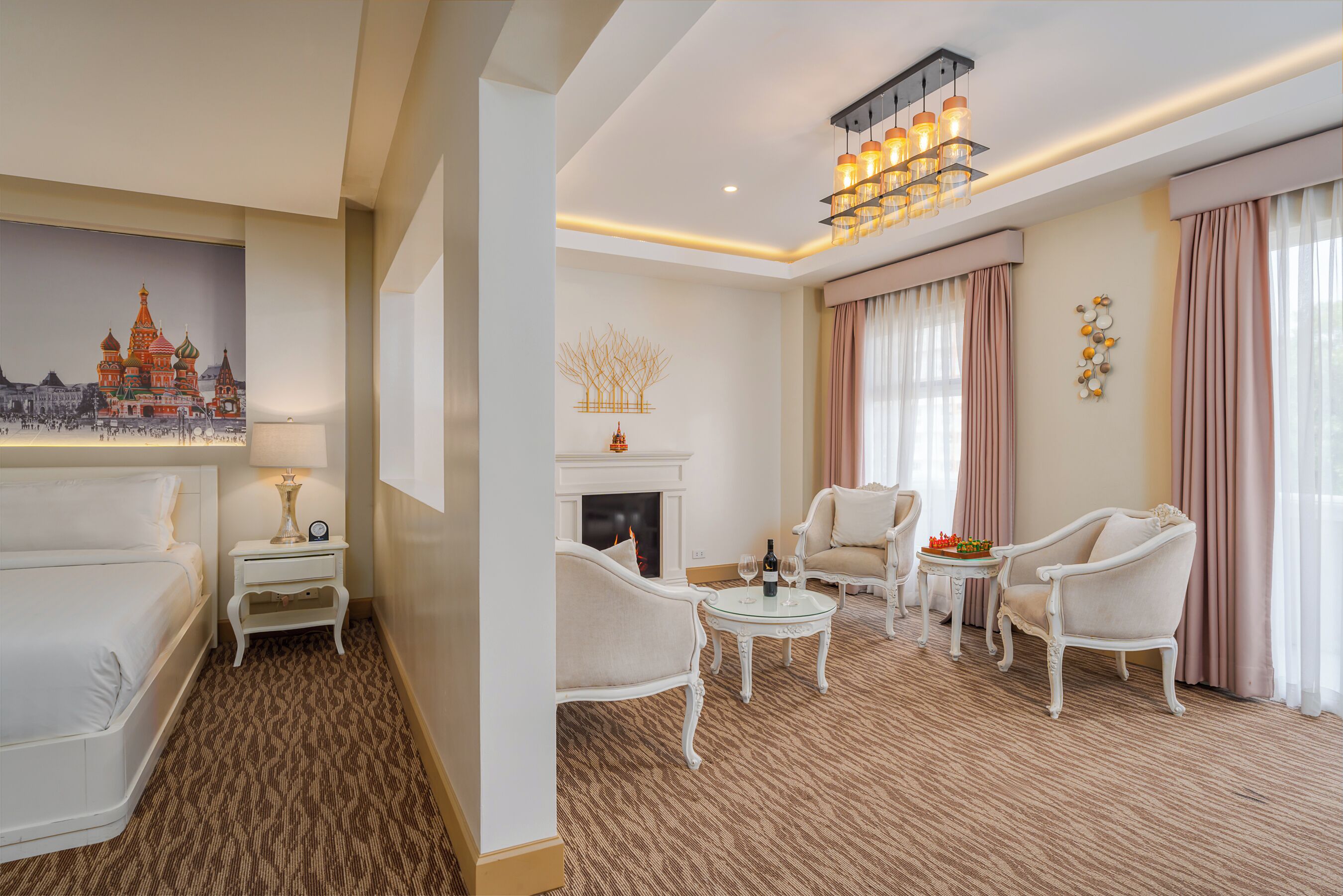A hotel room with a fireplace, white furniture, and a chandelier.