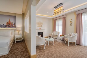 Una habitación de hotel con chimenea, muebles blancos y un candelabro.