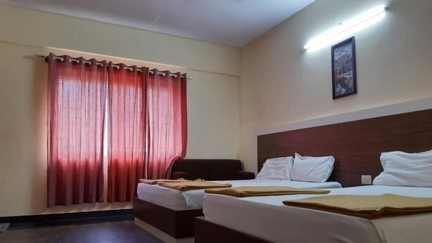 Habitación de hotel con dos camas, un ventanal grande con cortinas rojas, un cuadro en la pared y un cabecero de madera.