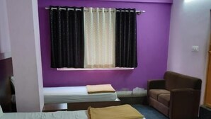 Una habitación con cama, una silla y una ventana con cortinas.