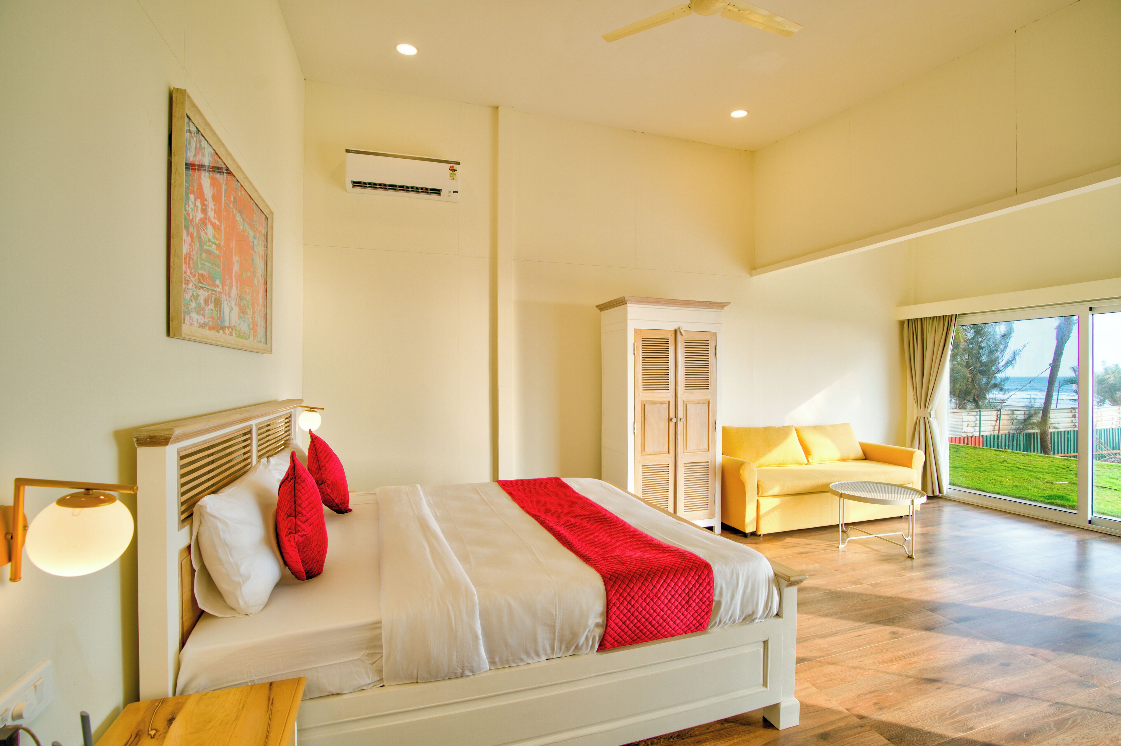 A spacious bedroom with a large bed, a sofa, and a view of the outdoors.