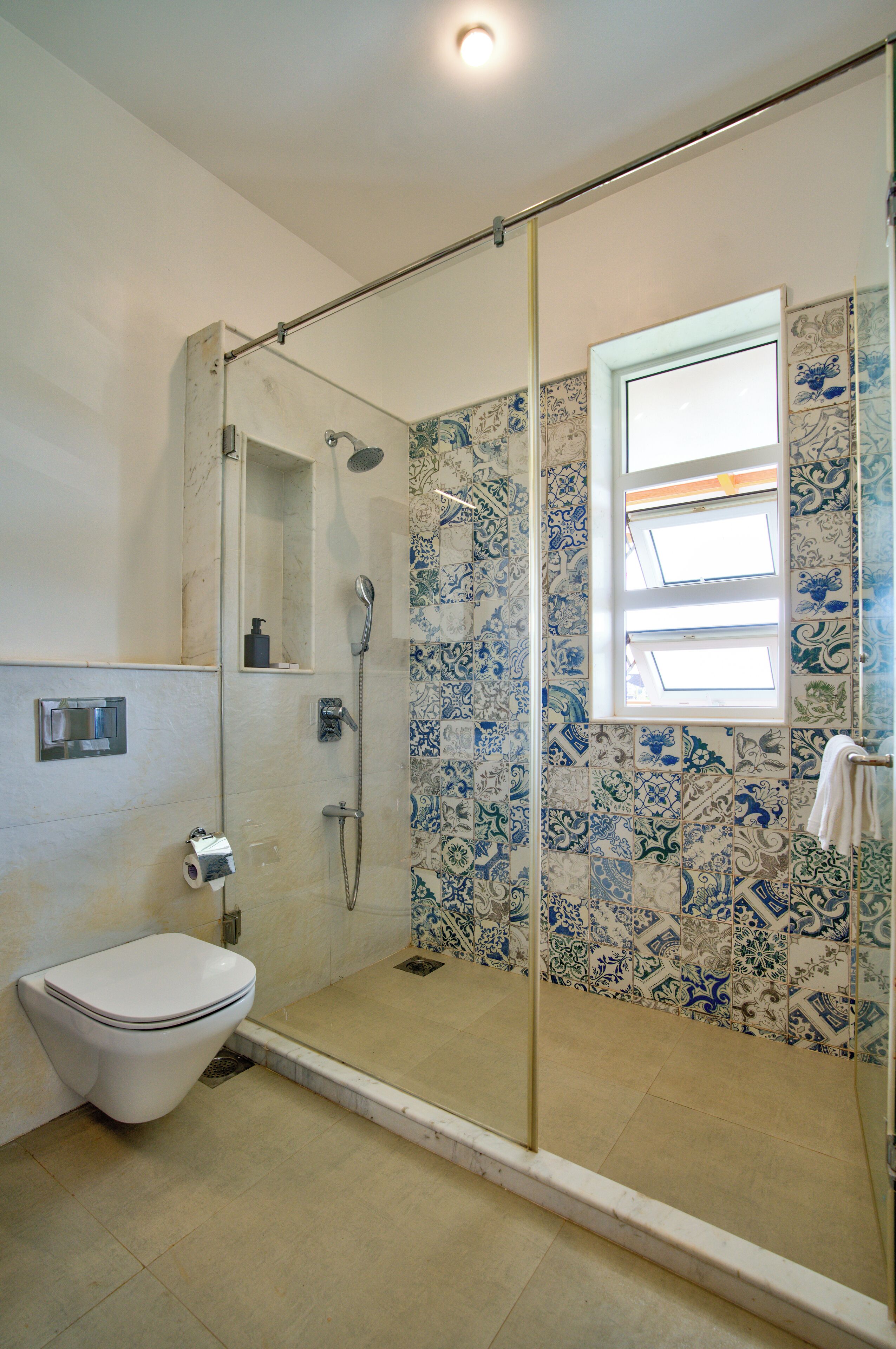 Une salle de bain avec une douche à parois de verre, des toilettes et une fenêtre.