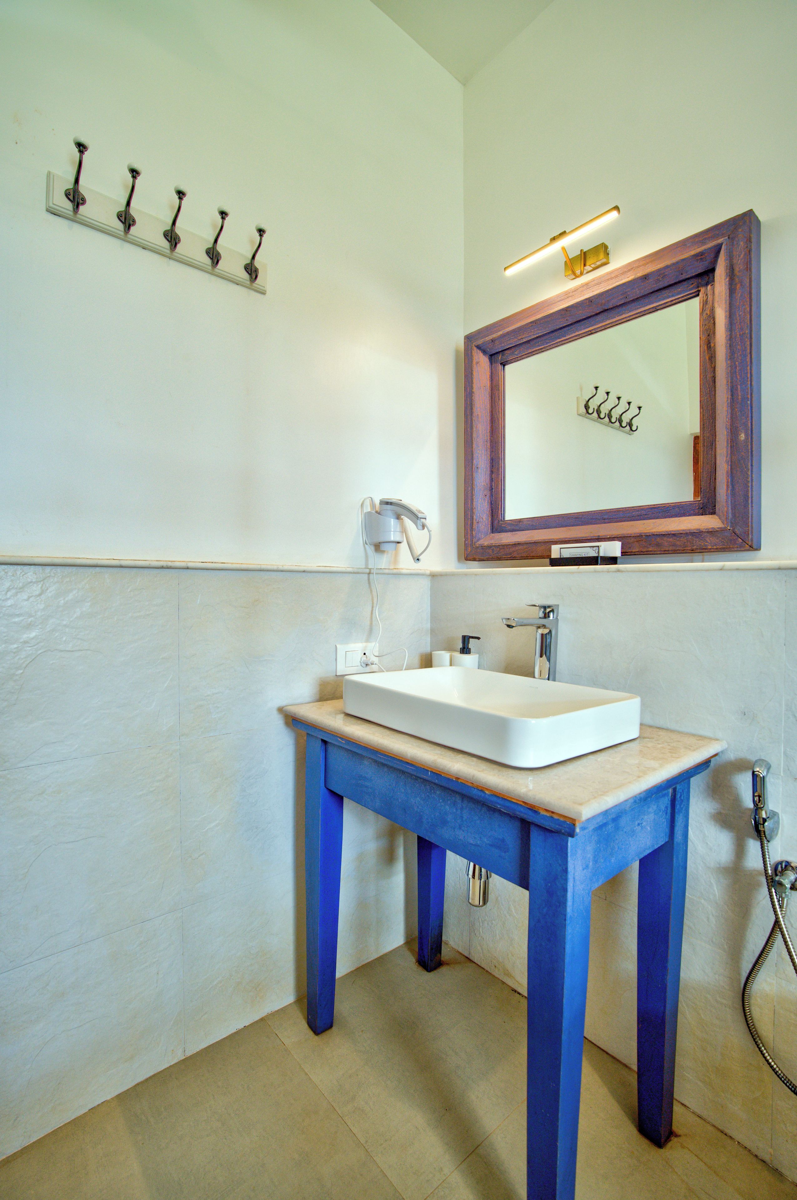 A bathroom with a white sink, blue table, and a wooden-framed mirror.