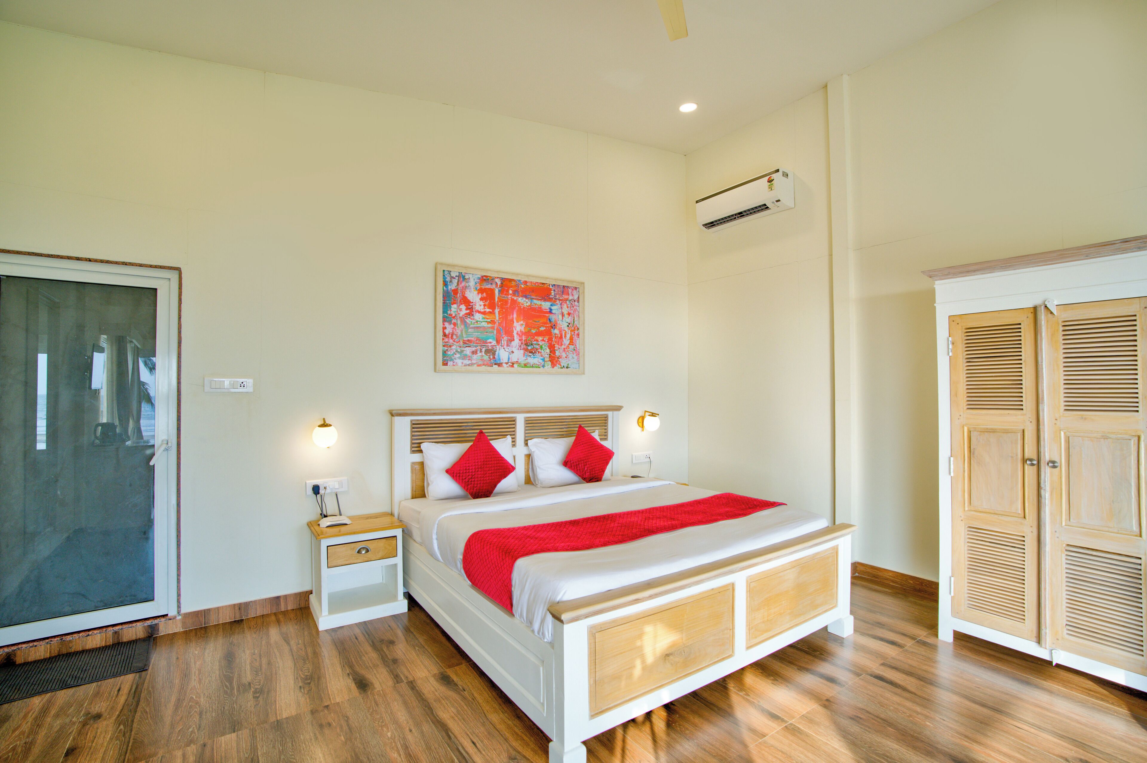 A bedroom with a bed, bedside tables, a wardrobe, and an air conditioning unit.