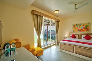 Habitación de hotel con una cama, un escritorio con botellas de agua, una silla y vistas al exterior.