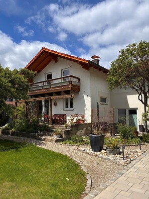 Une maison à deux étages avec un balcon, un jardin et une allée pavée.