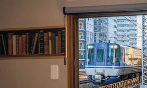Juna pysähtyneenä rakennuksen ulkopuolella, ja rakennuksen sisällä on kirjahylly.