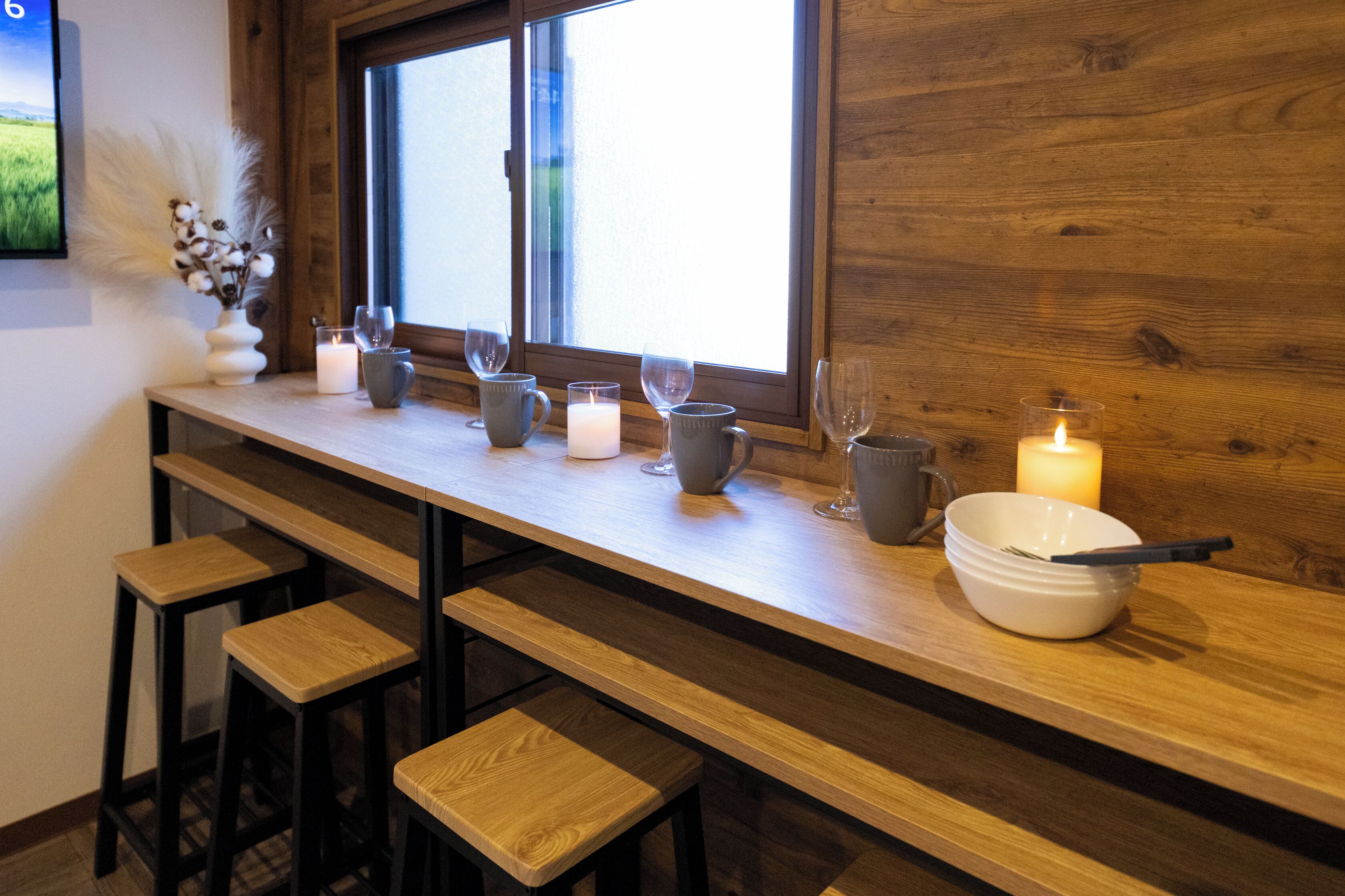 A wooden bar area with stools, candles, and glassware.