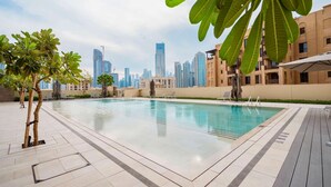 Una piscina en la azotea con vistas al horizonte de la ciudad, rodeada de palmeras y edificios modernos.