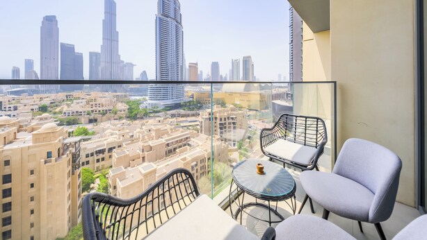 Un balcón con vista a la ciudad, incluyendo edificios altos y un cielo despejado.