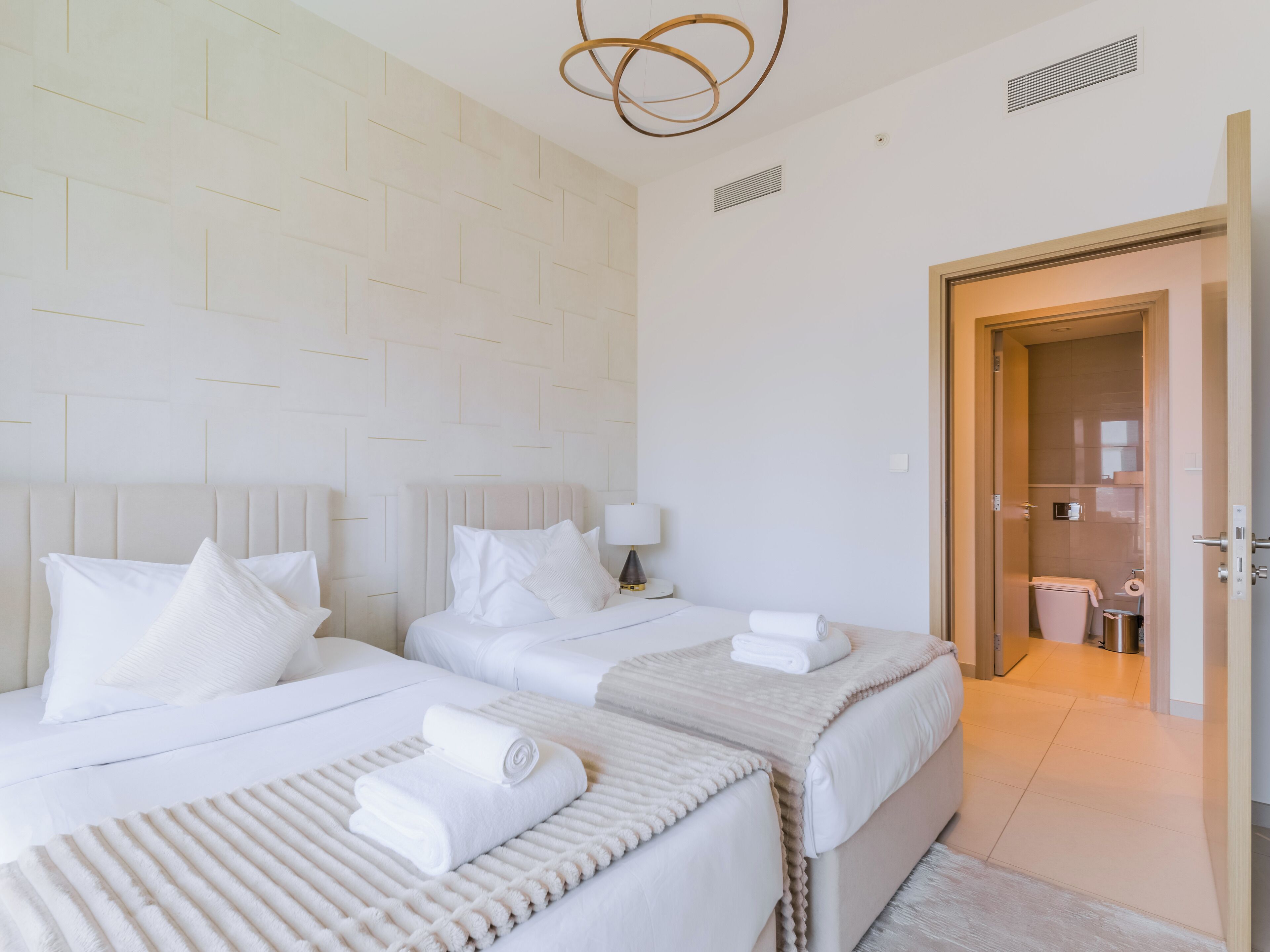 Une chambre d’hôtel avec deux lits, une salle de bain et une porte donnant sur une autre pièce.