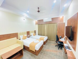 A hotel room with two beds, a sofa, a desk, a TV, and an air conditioning unit. - Hotel Sahara Tree (Bengaluru)