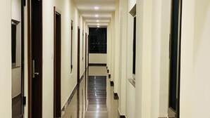 A long, narrow hallway with doors on both sides, leading to a staircase at the end. - Hotel Sahara Tree (Bengaluru)