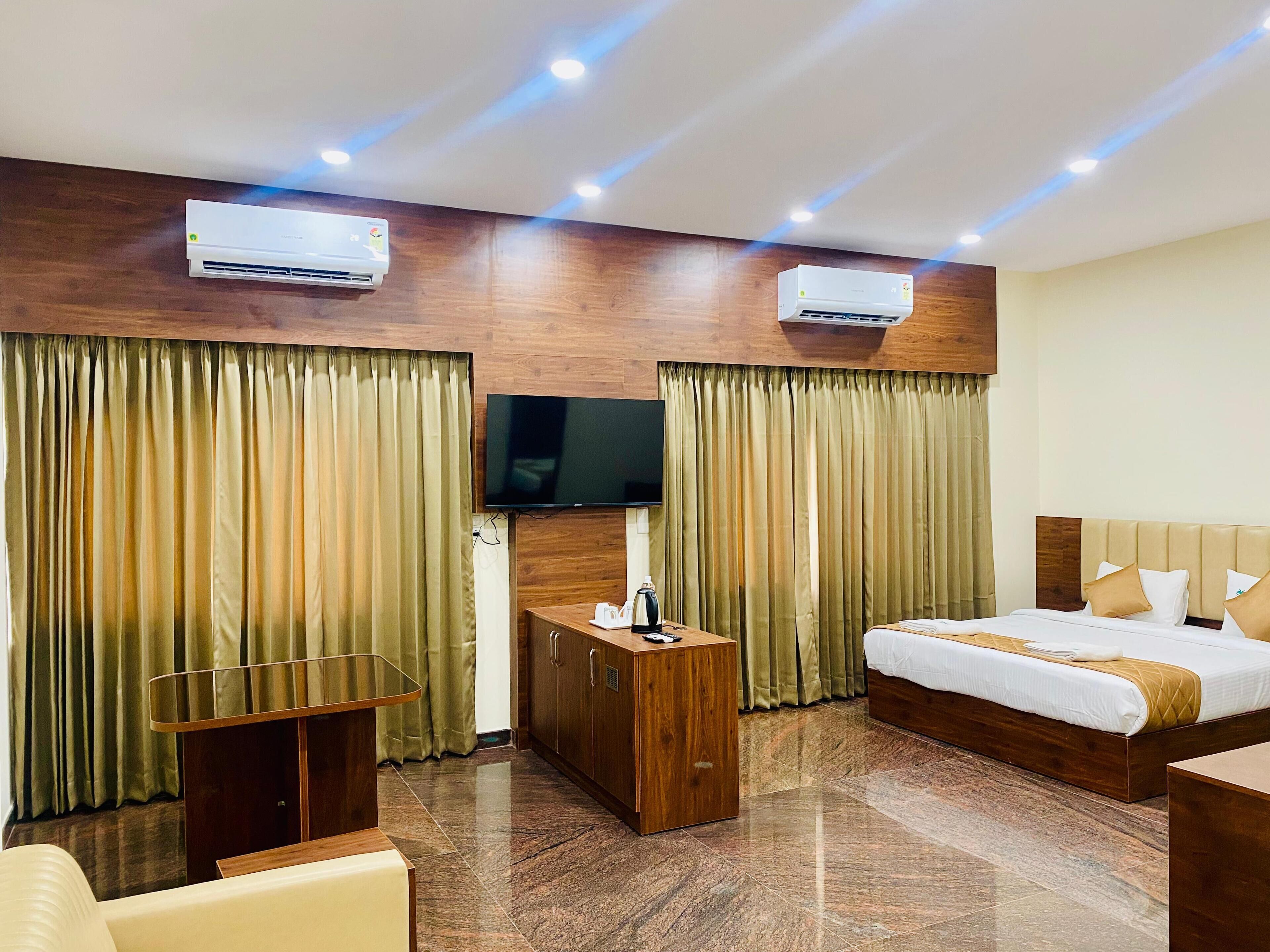Habitación de hotel con cama, televisor, armario de madera y una pequeña mesa.