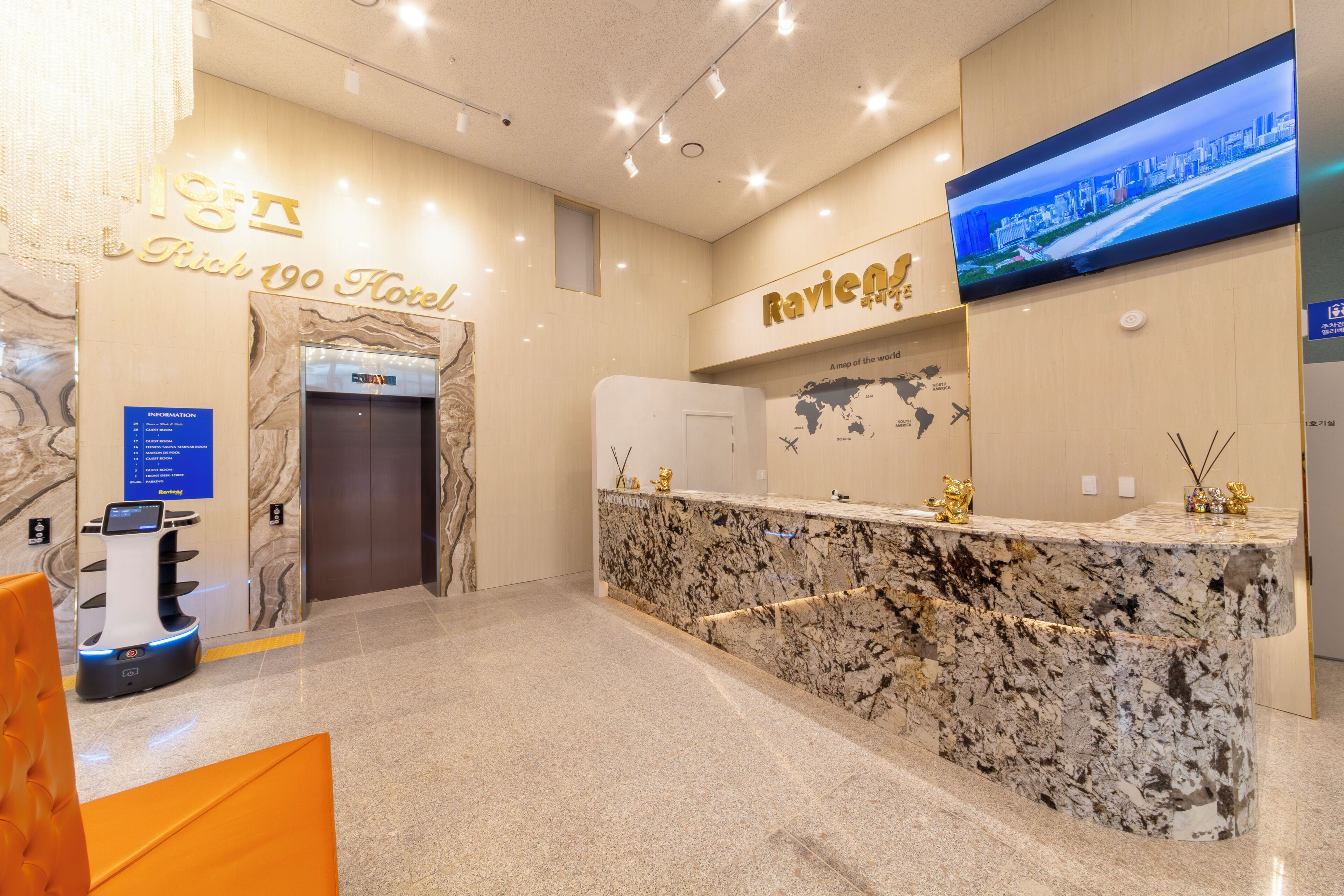 A hotel reception area with a marble counter, a digital kiosk, and a television displaying a cityscape.