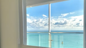 Une chambre dotée d’une grande fenêtre donnant sur une piscine et la mer.