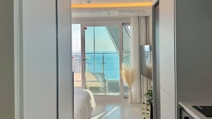 Une chambre d’hôtel moderne dotée d’un balcon, d’un lit, d’une télévision et d’un coin cuisine.
