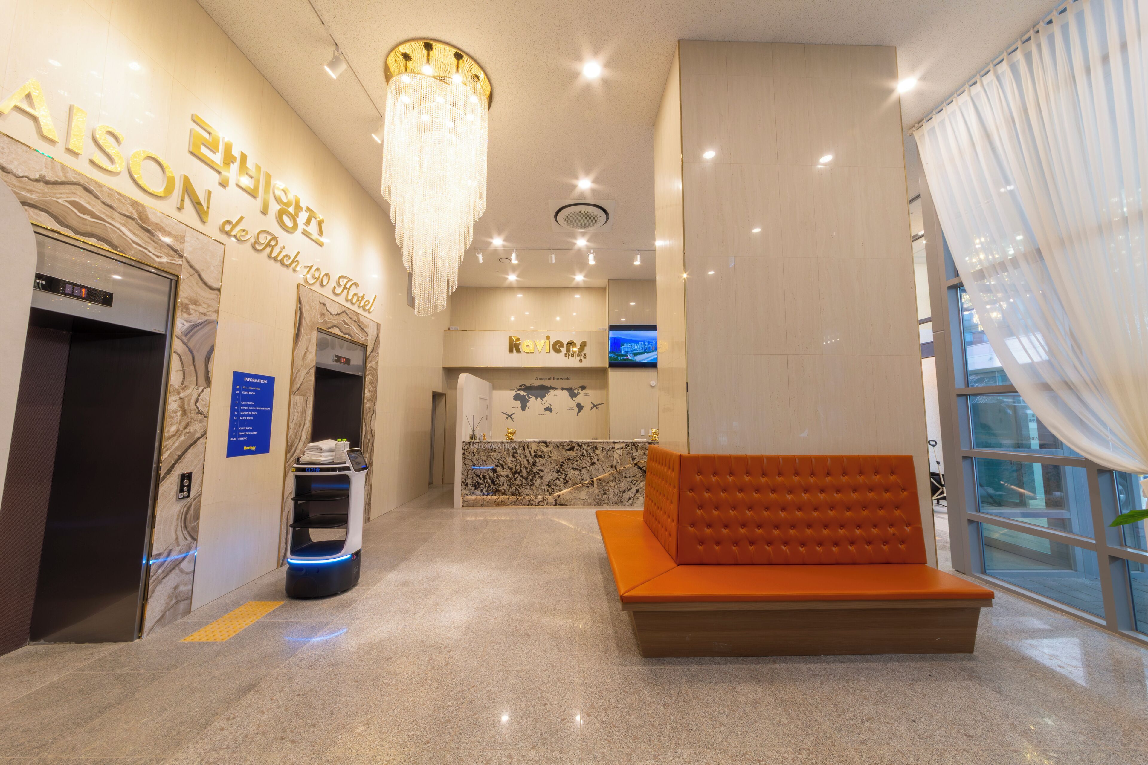 A hotel lobby with a reception desk, a seating area, and a self-service kiosk.