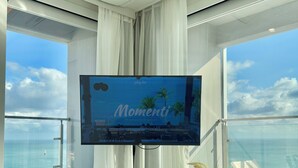 Une chambre moderne dotée d’un grand écran de télévision affichant « Momenti » et offrant une vue sur la mer.