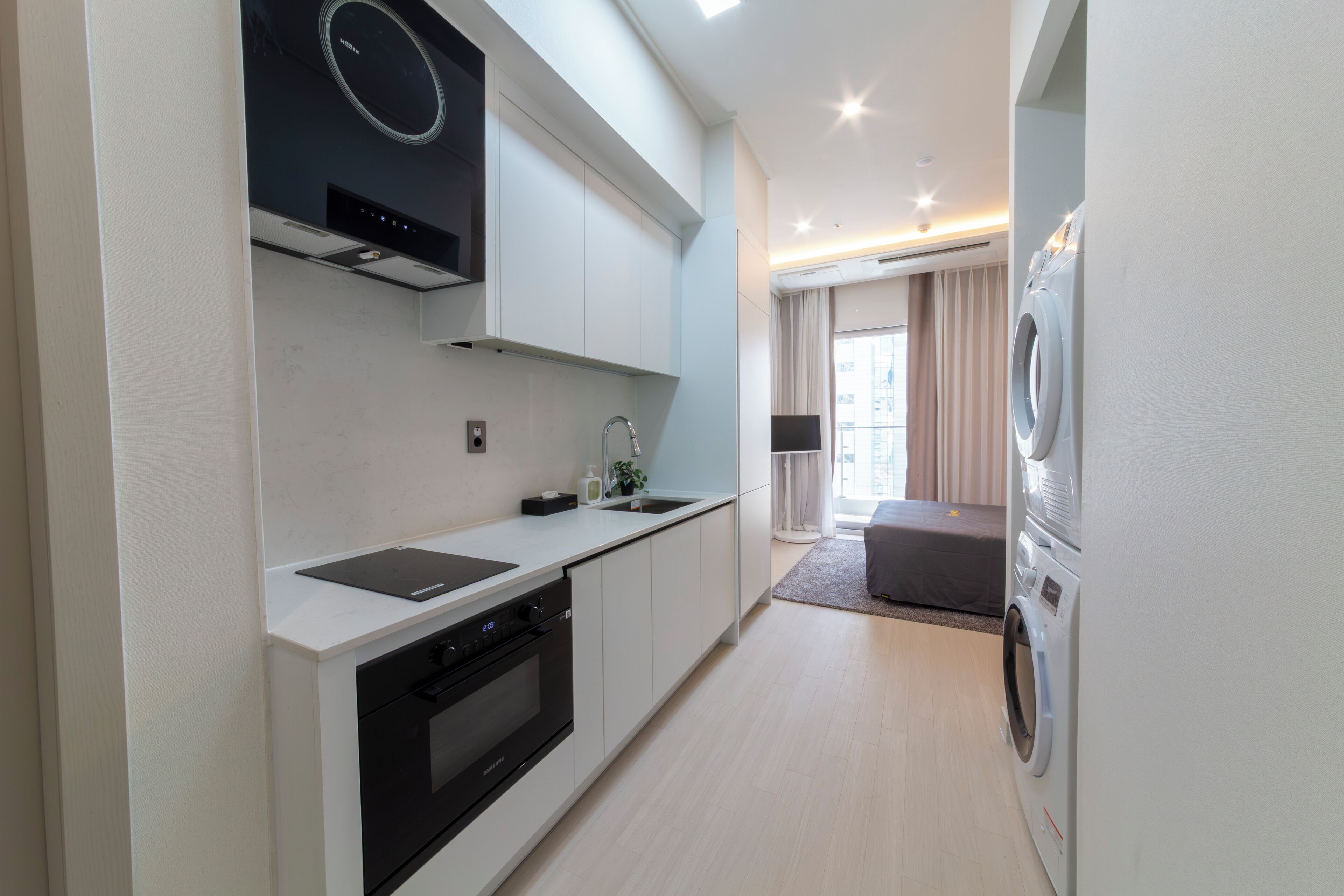 Eine moderne Küche mit integrierten Geräten, ein Essbereich mit einer Couch und einer Waschmaschine.