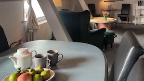 A cozy dining area with a table set for two, featuring a white teapot, two mugs, and a plate of fruit. - Apartment in rural idyll (Vamdrup)