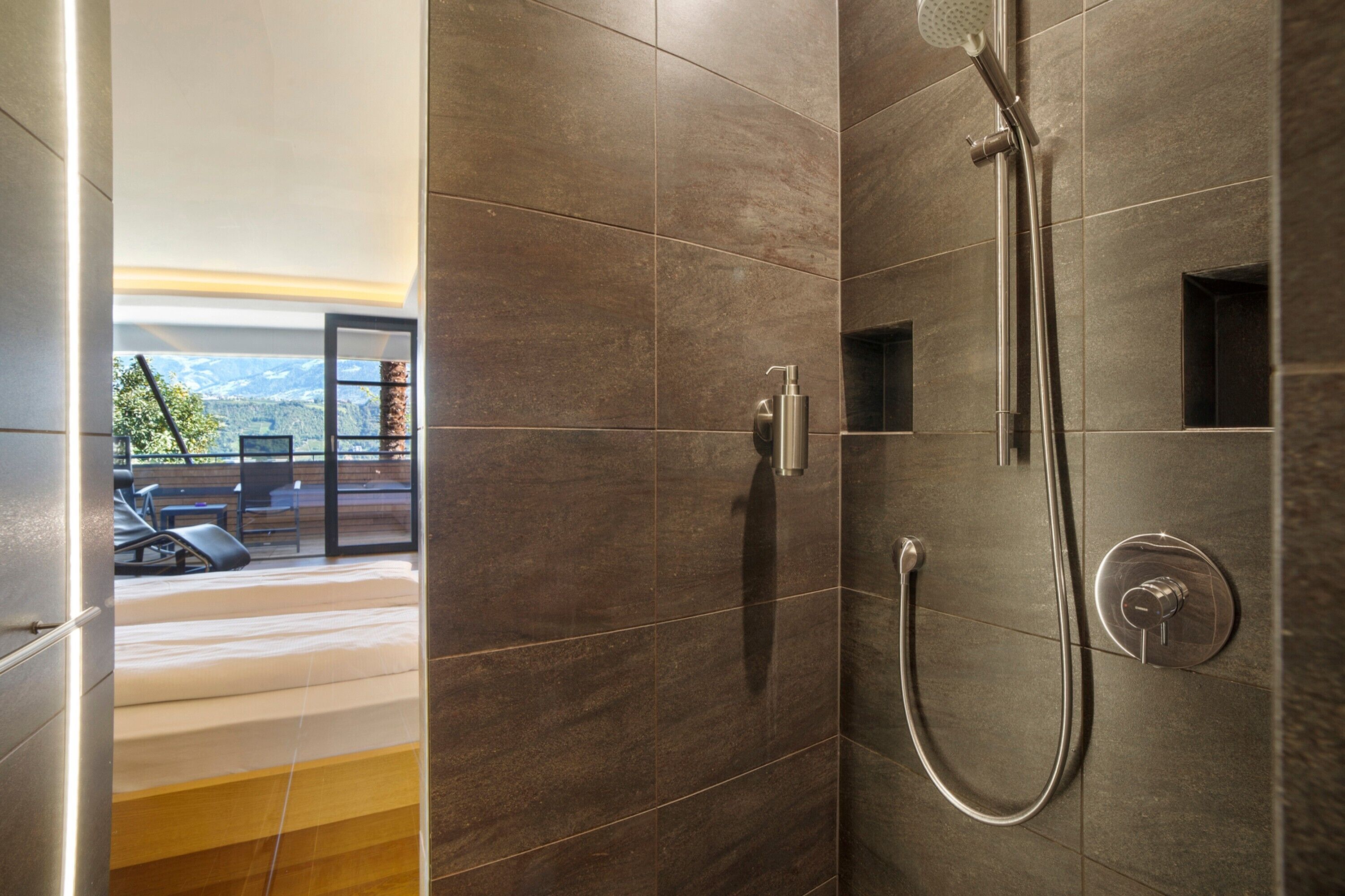 Une douche équipée d’un pommeau de douche à main et de commandes murales.