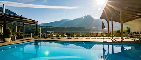 A swimming pool with lounge chairs and a mountain view.