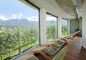 Une pièce moderne avec de grandes fenêtres, un plancher en bois et une rangée de fauteuils confortables.
