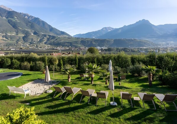 Un jardín con asientos al aire libre y vistas a montañas.