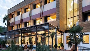 Een modern hotel met een overdekt buitengebied, meerdere verdiepingen en grote ramen.