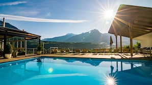 Piscina con sillas de descanso y vista a la montaña.