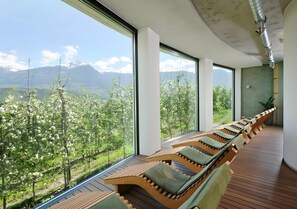 Une pièce moderne avec de grandes fenêtres, un plancher en bois et une rangée de fauteuils confortables.