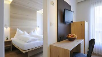Habitació d'hotel amb llit, escriptori, cadira, televisió i un plat de fruita.