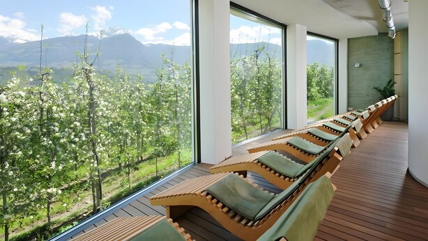 Une pièce moderne avec de grandes fenêtres, un plancher en bois et une rangée de fauteuils confortables.