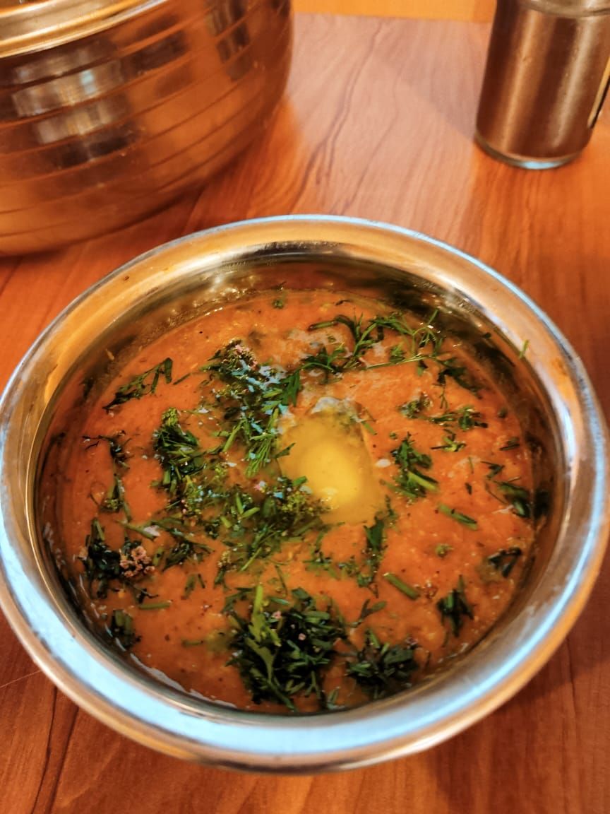 A bowl of soup garnished with herbs, placed on a wooden table.