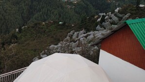Une vue panoramique depuis un point d’observation élevé, surplombant un paysage montagneux avec de vastes forêts et quelques bâtiments dispersés.