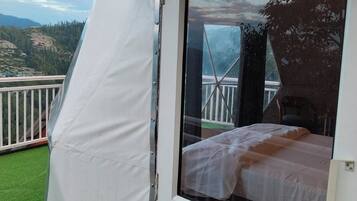 Una habitación con cama, ventana y vistas a un balcón.